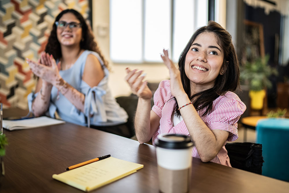 Woman with disability at a work meeting clapping - unified work