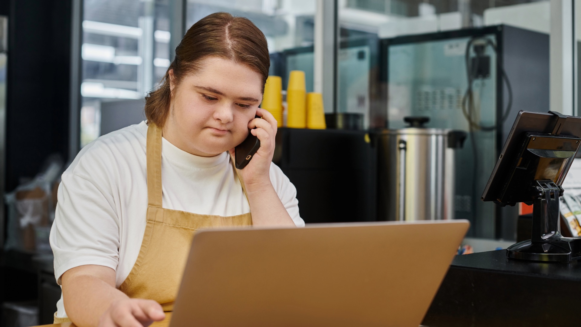 Young woman with disability at work talking with a customer on the phone while looking up the customer's order